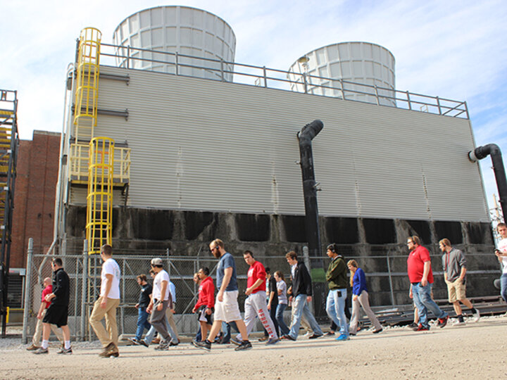 Visitor's guide, people walking past utility plant